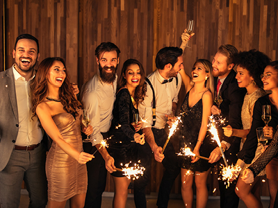 Group of people with champagne flutes and sparklers celebrating end of year
